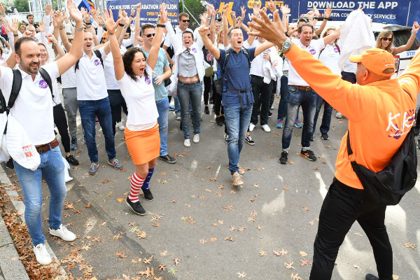 juichende deelnemers met handen omhoog in witte KiKa polo en begeleider.